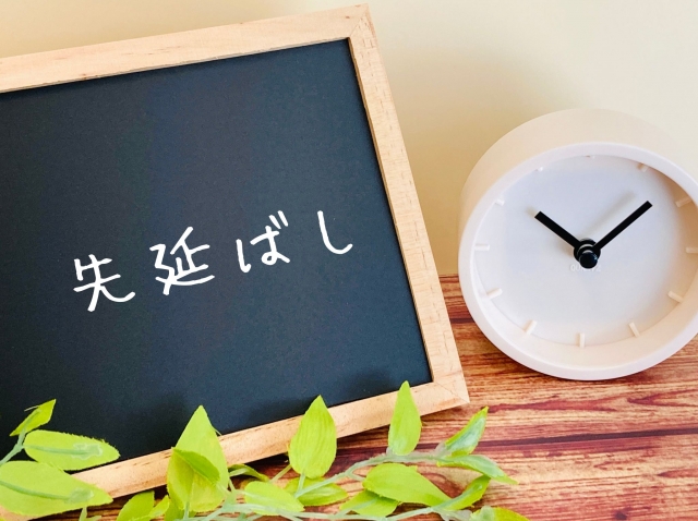 黒板に「先延ばし」の文字と時計